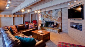A cozy living room with a leather sofa, a fireplace, a television, and a stone accent wall. - 6 Bedroom + 2 Den Duplex 2 Blocks from PC Mountain! Can't beat this place! (Park City)