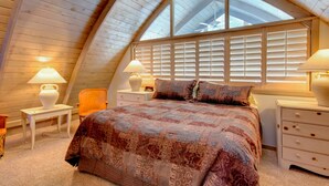 A bedroom with a sloped ceiling, a large bed with patterned bedding, two bedside lamps, a chair, and a window with blinds. - 6 Bedroom + 2 Den Duplex 2 Blocks from PC Mountain! Can't beat this place! (Park City)