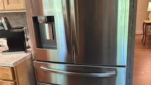 Un refrigerador de acero inoxidable con dispensador de agua y hielo, horno empotrado y compartimento congelador.