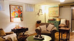 Un salón acogedor con un tapete redondo tejido, una mesa de centro verde, un sofá marrón y una mesita de noche con una lámpara.