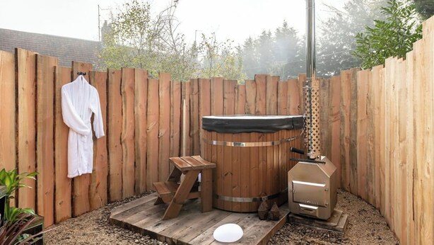 A wooden deck with a sauna, a bench, and a hanging robe. - Beautiful hut in countryside garden with wood fired hot tub near Bath & Frome (Wingfield)