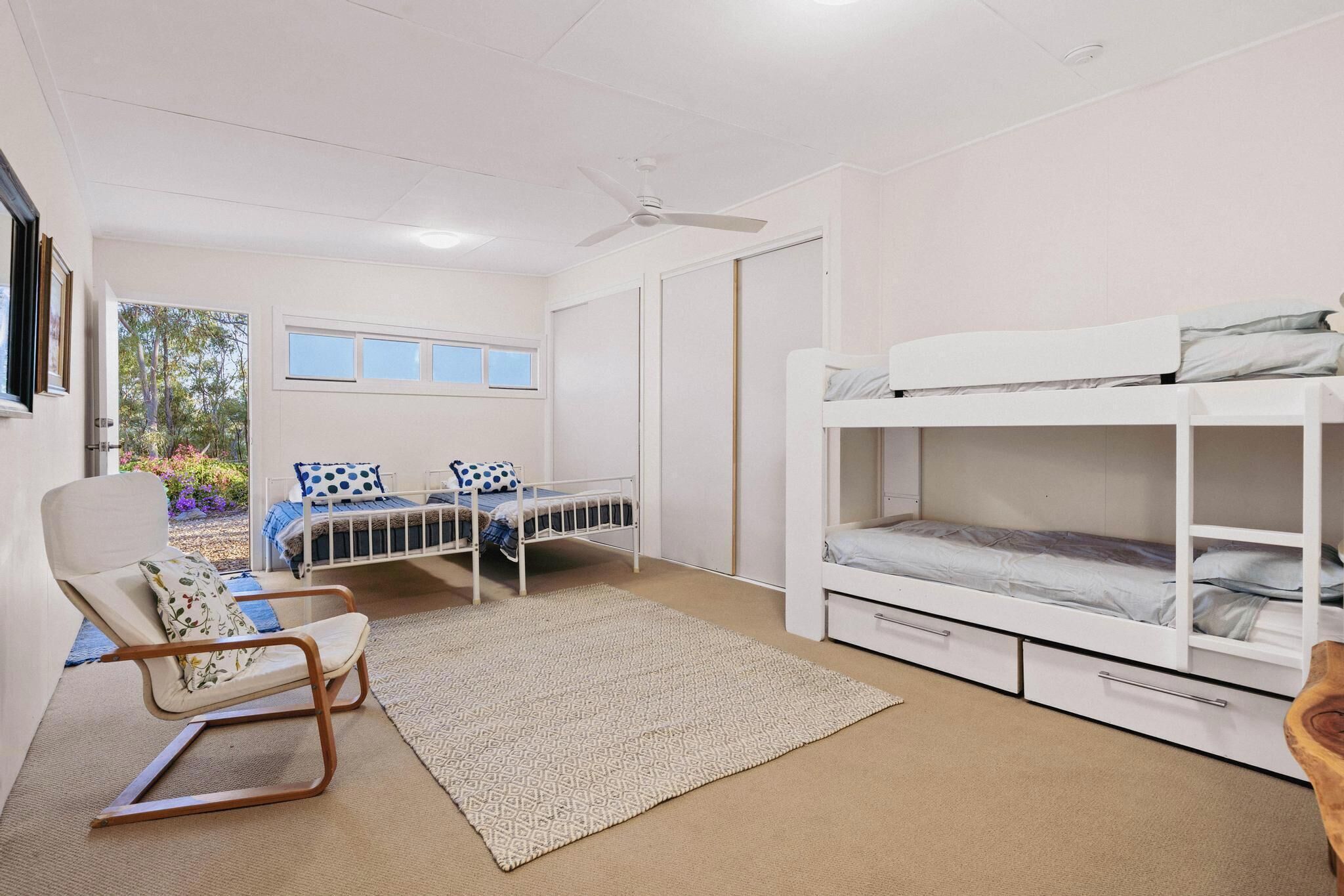 Une chambre avec deux lits, une chaise, un ventilateur de plafond et une fenêtre.