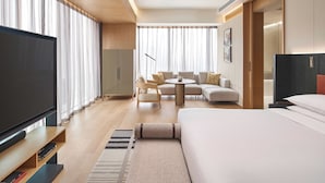 Een moderne hotelkamer met een grote flatscreen televisie, een bank, een rond bijzettafeltje en een bed.
