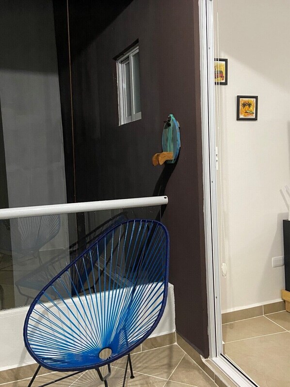 A room with a blue wire chair, a small window, and a door with a white frame.