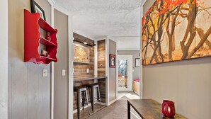 A hallway with a red shelf, a wooden bar area, and a painting on the wall.
