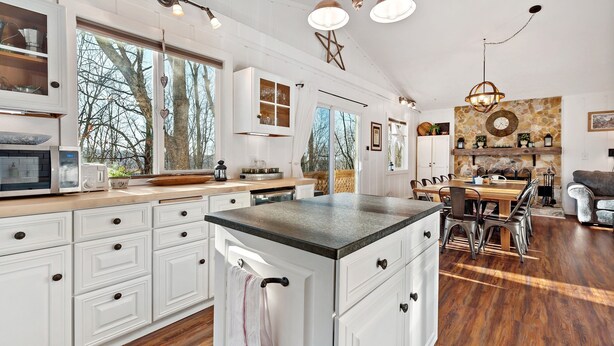 A spacious kitchen with white cabinetry, a central island, and a dining area with a wooden table and chairs.