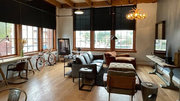 Un salon spacieux avec une grande fenêtre, un canapé, une table basse et un vélo.