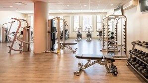 Een fitnessruimte met diverse trainingsapparaten, waaronder loopbanden, krachttrainers en gewichten.