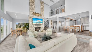 A spacious living area with a stone fireplace, a large sofa, and a dining table.