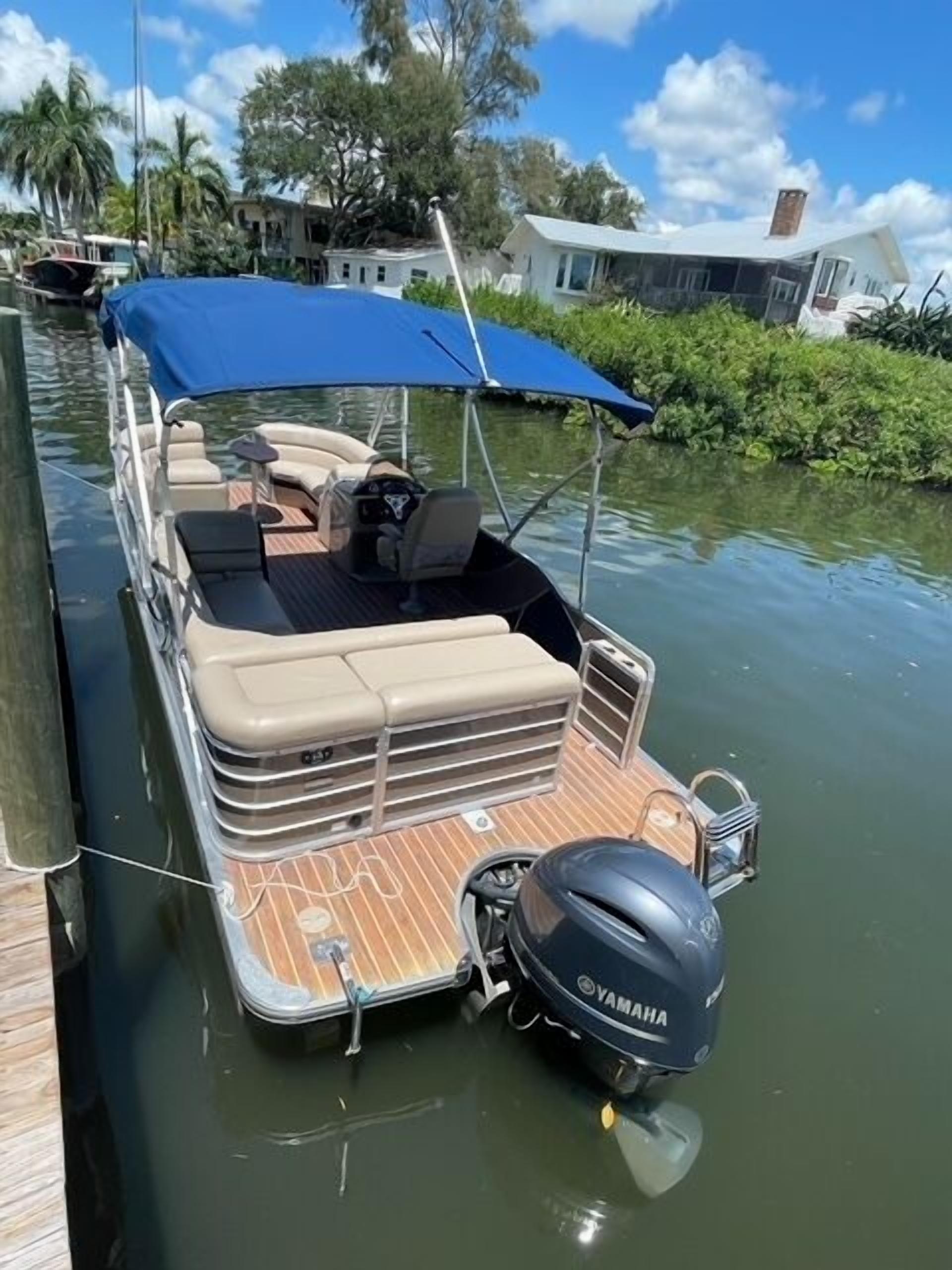A boat with a blue canopy, seating area, and Yamaha outboard motor.