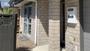 A two-story house with a brick exterior, a covered porch, and a garage door. - Townhouse Near City Centre, River & Stadium (Waikato)