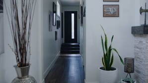 Un couloir doté d’un plancher en bois, de tableaux encadrés accrochés aux murs et de plantes en pot.