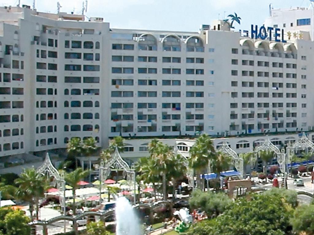 Un edificio de hotel de varios pisos con un llamativo letrero que dice 'HOTEL' en la esquina superior derecha.