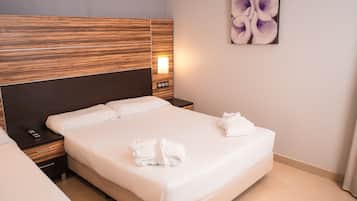 Habitación de hotel con una cama grande, una mesita de noche con lámpara y una obra de arte colgada en la pared.