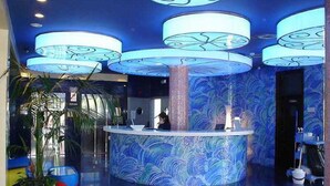 A reception area with a central counter, large blue patterned walls, and a modern design. - Magic INN (Oropesa del Mar)