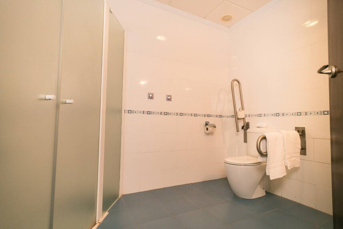 A bathroom with a toilet, a shower, and a towel rack.