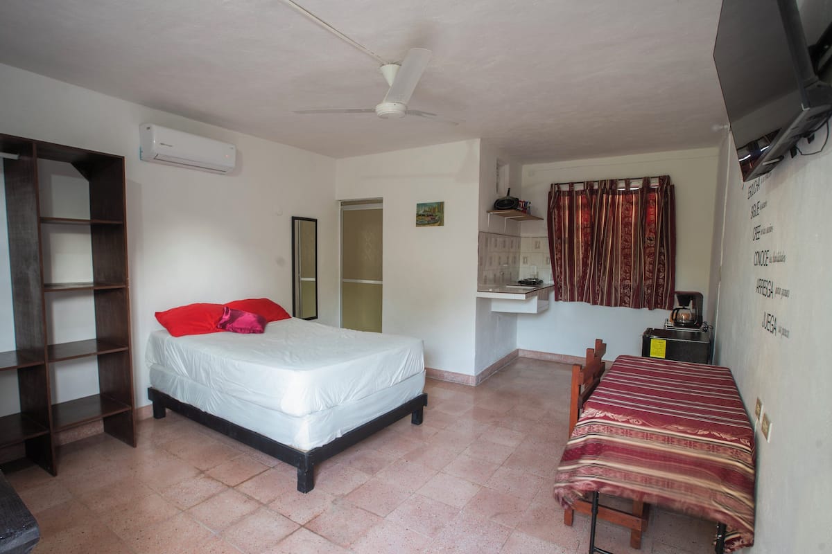 A bedroom with a bed, a desk, a chair, a wardrobe, and a ceiling fan.