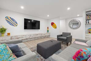 A modern living room with a flat-screen TV, a fireplace, and a bookshelf.