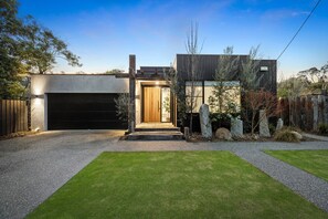 A modern house with a garage, a wooden front door, and a well-maintained lawn.