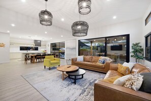 A spacious living area with a modern kitchen, a dining set, and a large window offering a view of the outdoors.