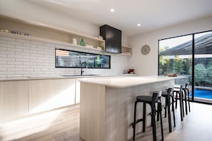 Cozinha moderna com uma ilha grande, azulejos brancos tipo metrô e TV embutida.