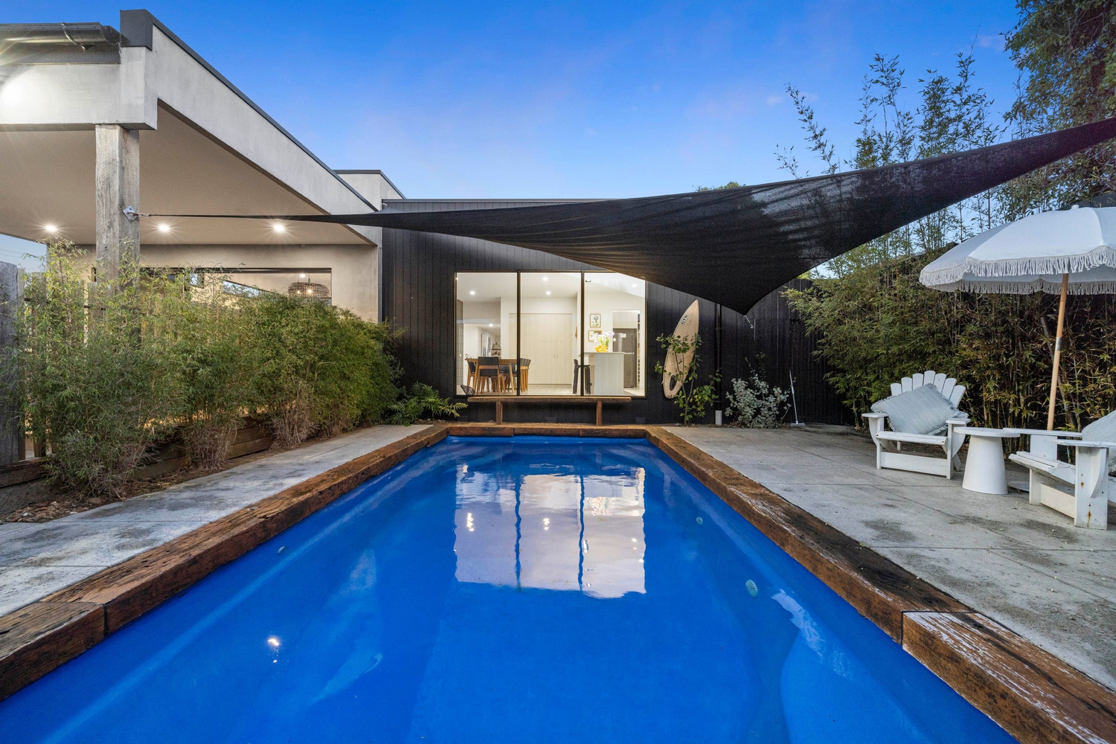 A modern house with a swimming pool, outdoor seating, and a covered patio.