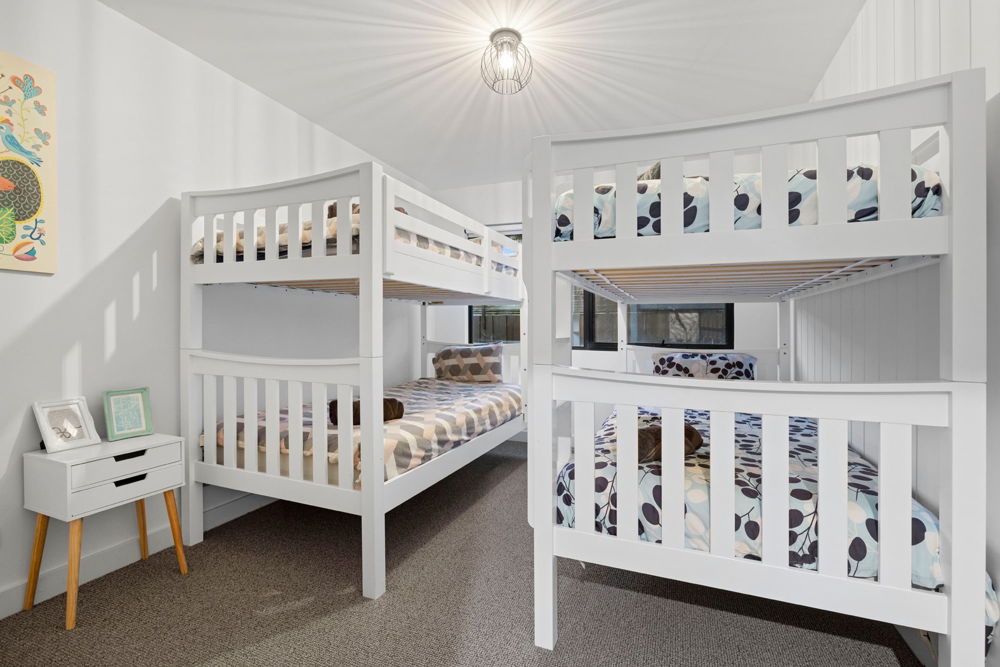 Ein Kinderzimmer mit Etagenbett, kleinem Schreibtisch und einem gerahmten Bild.