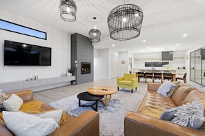 A modern living room with a fireplace, a dining area, and a kitchen.