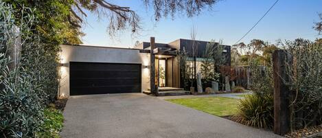 A modern house with a garage, a well-maintained lawn, and a variety of plants.