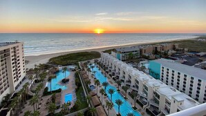 Een resort met meerdere zwembaden, een strand en uitzicht op de zonsondergang.