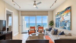 Un soggiorno moderno con televisione, angolo relax e un'ampia finestra con vista sull'oceano.