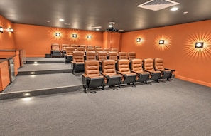 A theater with rows of seats, a staircase, and wall-mounted lights.