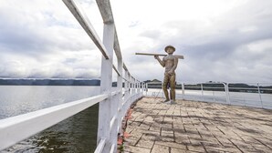 Una estatua en un paseo marítimo con barandilla blanca y un camino pavimentado.
