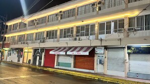 Un edificio de varios pisos con un restaurante en la planta baja y varias tiendas cerradas.