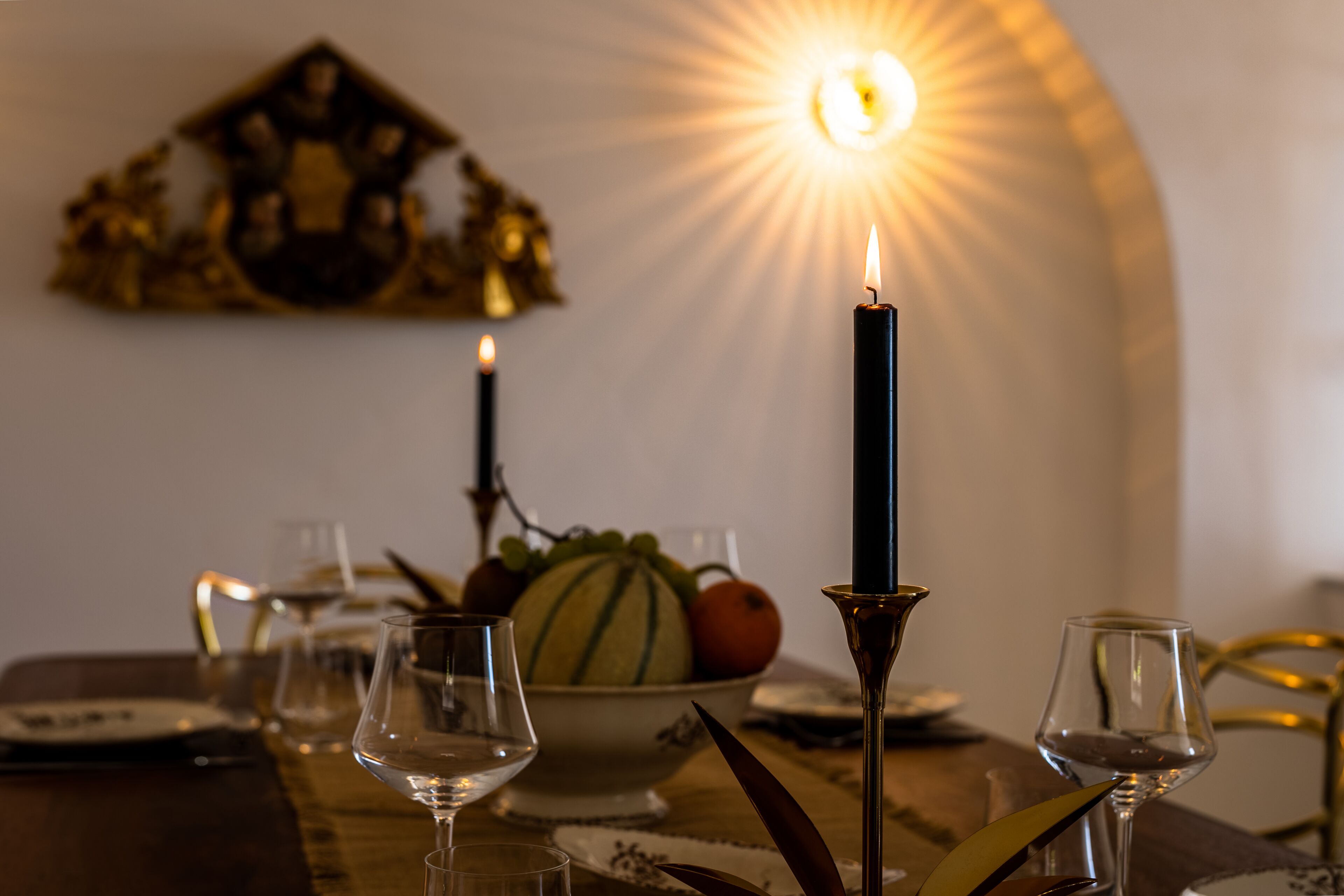 A dining table with candles, a fruit bowl, and wine glasses.
