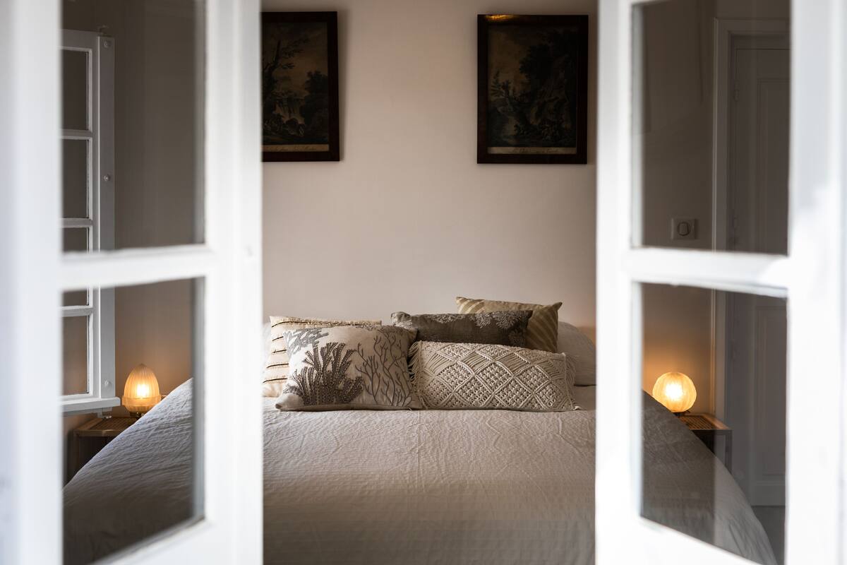 Un dormitorio con cama, almohadas y lámparas de pared.