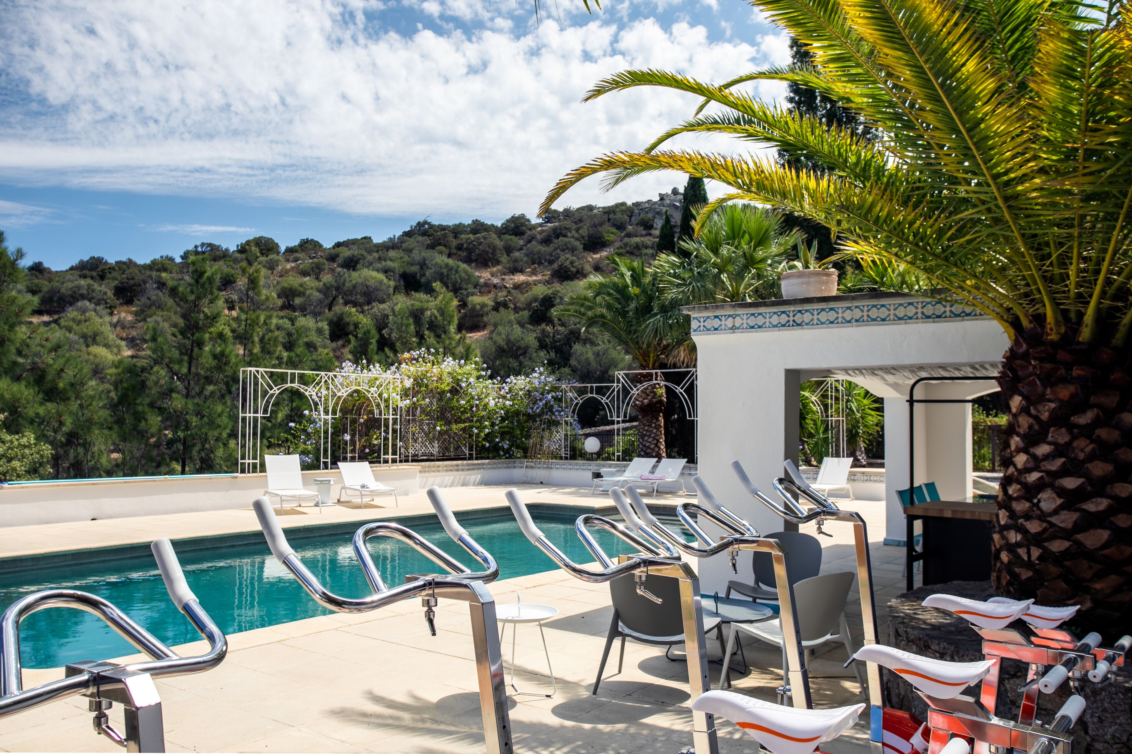 Zona de piscina con sillones de descanso y vista a una colina.