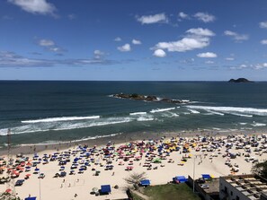 A beach with numerous umbrellas and people.