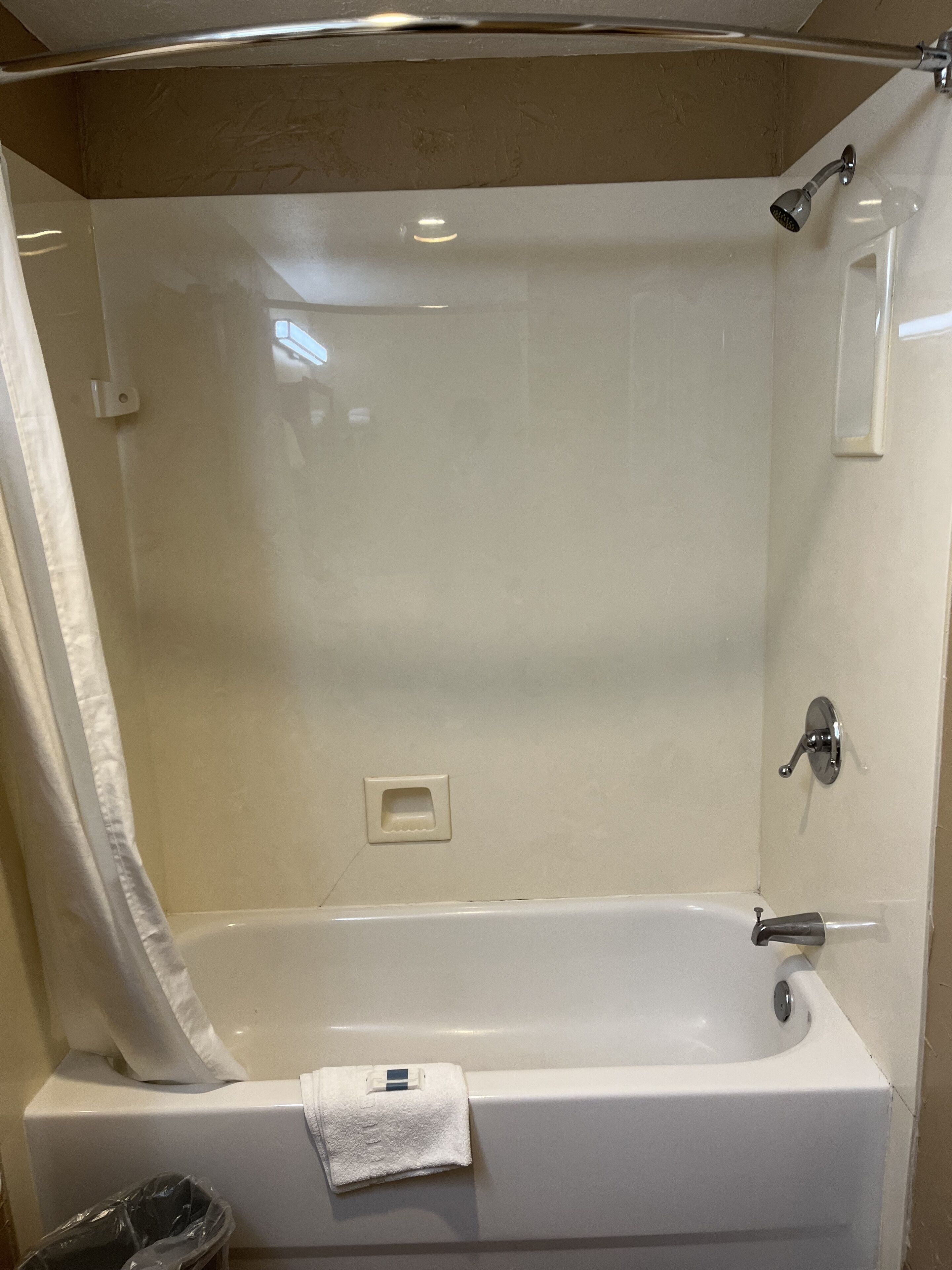 Una bañera blanca con un cabezal de ducha y un perchero para toallas.