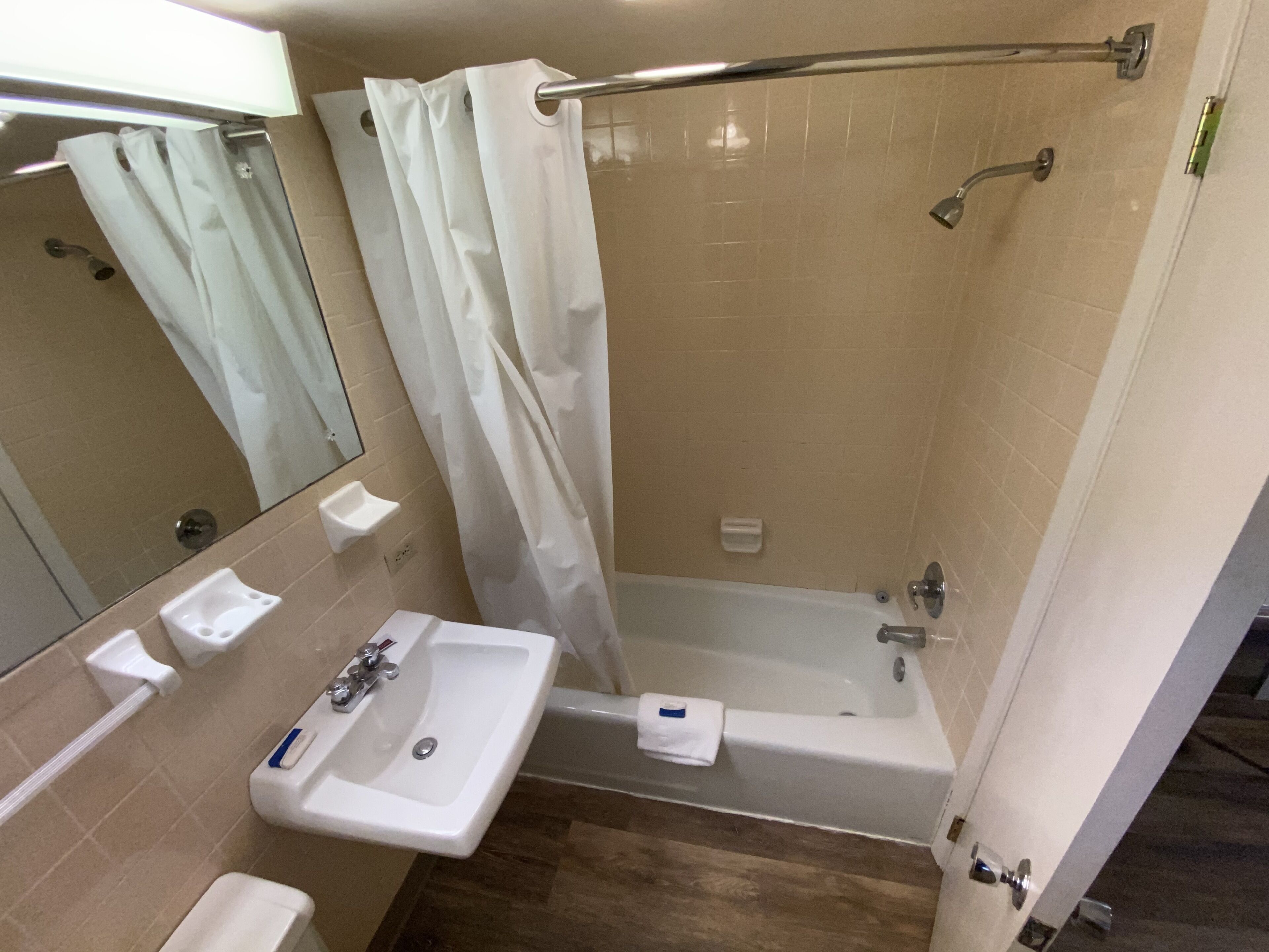 A bathroom with a sink, mirror, shower, and bathtub.