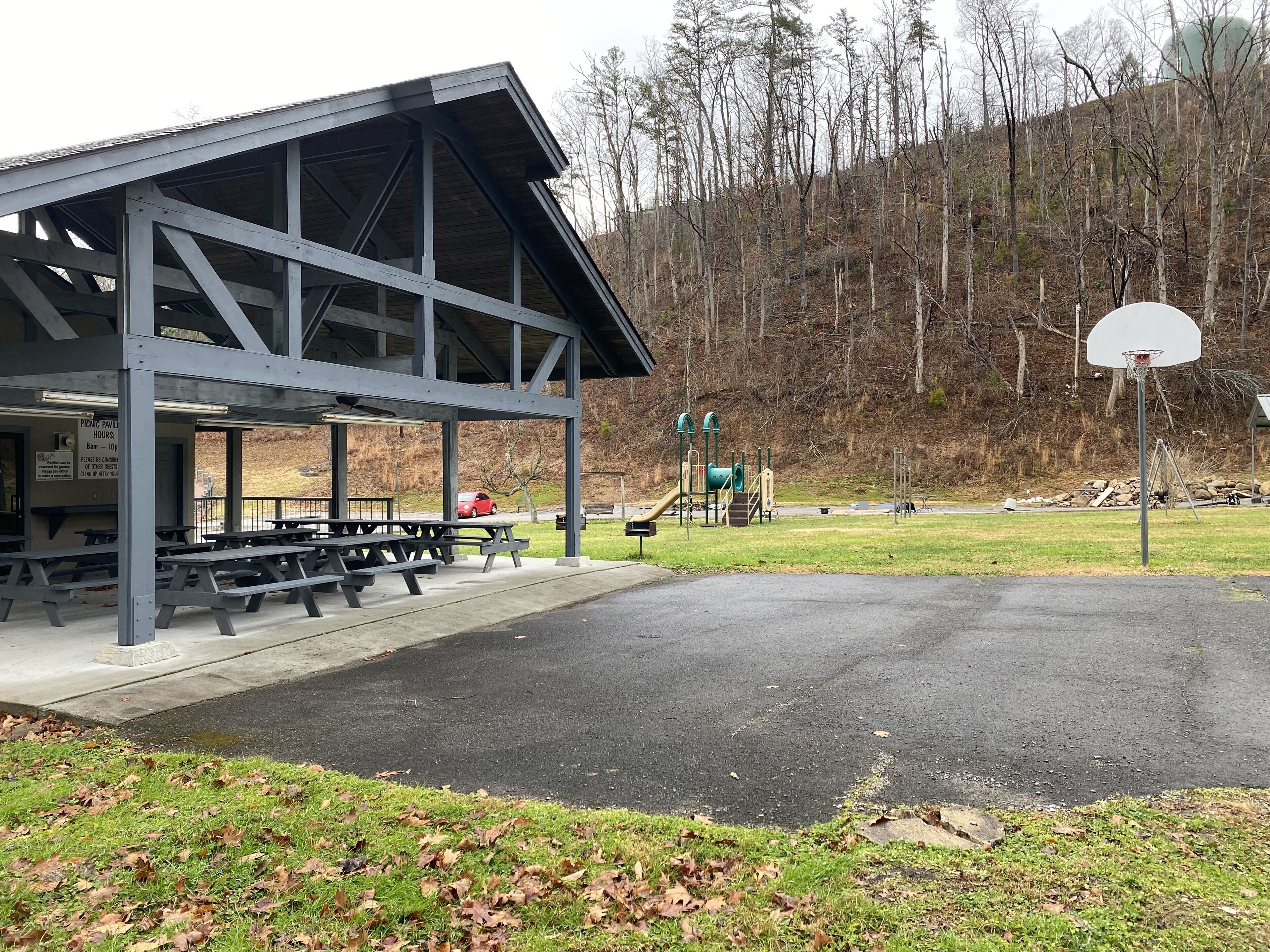 A picnic pavilion with benches and a basketball hoop.
