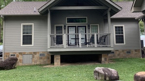 A two-story house with a covered porch, stone foundation, and a stone chimney. - Carr's Northside Motel and Cottages (Gatlinburg)