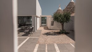 Un edificio moderno con una estructura de techo de piedra, un área de descanso con mesas y sillas, y cielo despejado.