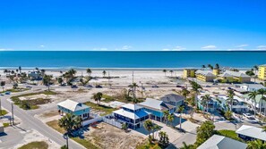 Uma área costeira com edifícios, uma praia e um céu azul límpido.