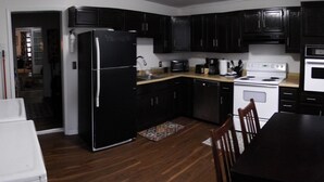 Una cocina con armarios negros, un refrigerador, una estufa y una lavadora.