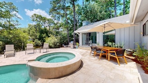 Quintal com piscina, móveis de pátio e área de estar coberta.