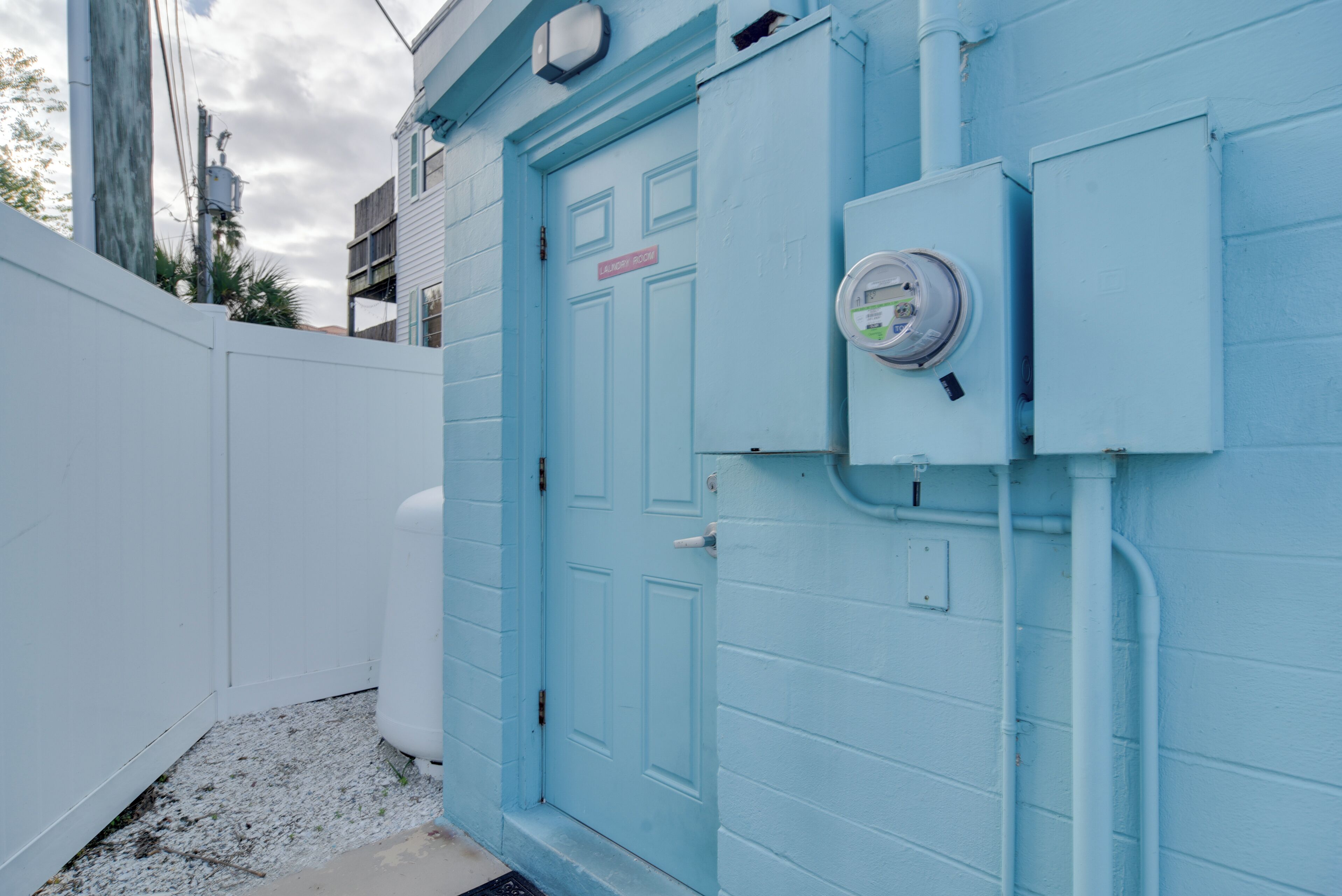 Una porta blava amb un rètol que diu "ALLEY ROOM" i un comptador de subministraments a la paret.