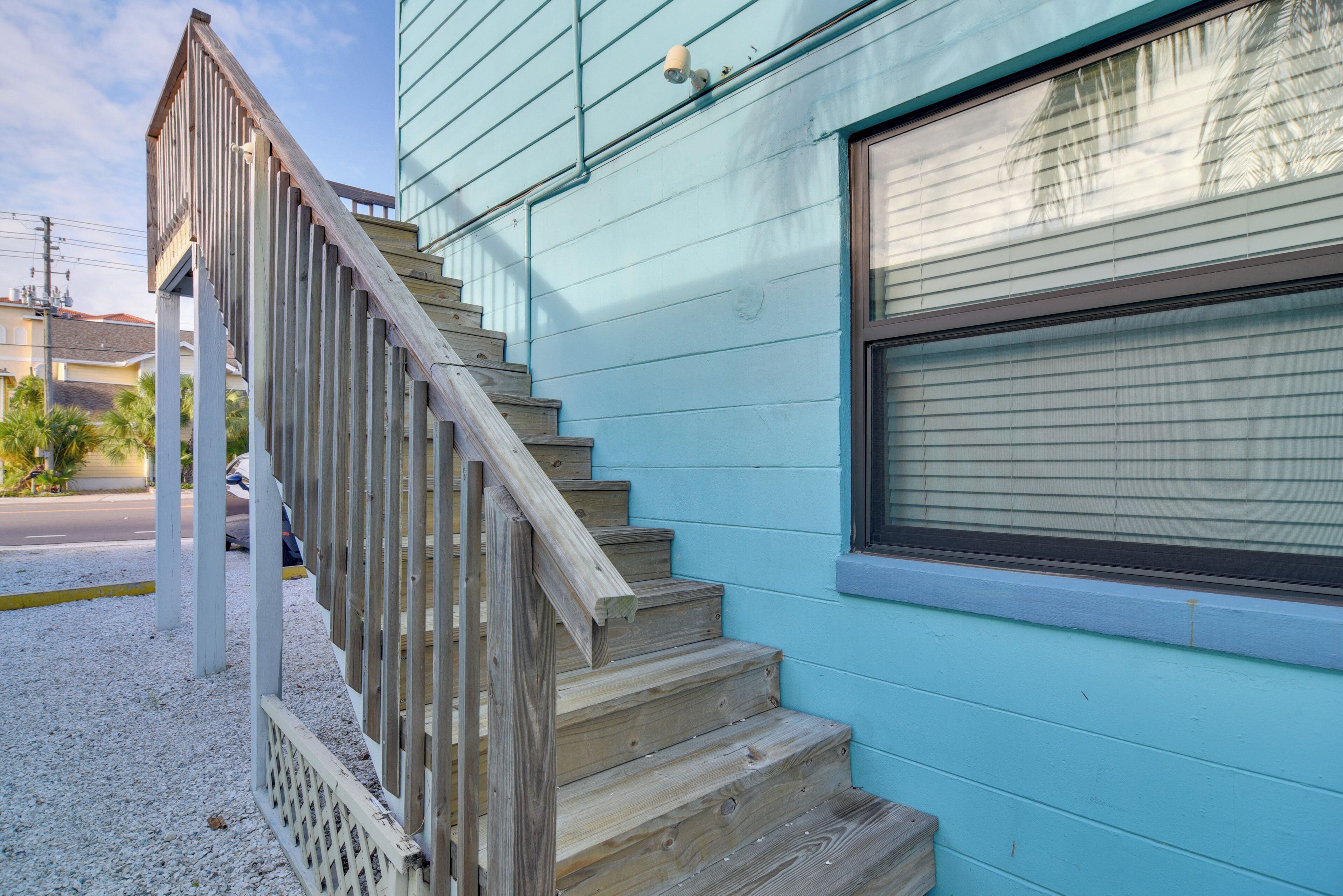 Un escalier en bois mène à une maison bleue dotée d’une fenêtre.