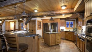 Maalaishenkinen keittiö, jossa on puukaapit, suuri keittiösaareke ja iso jääkaappi.