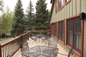 A deck with outdoor furniture, a wooden railing, and a building with large windows.